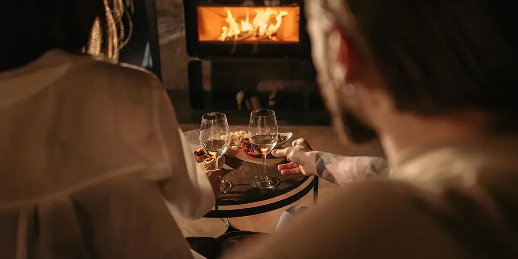 Un couple profite de la chaleur d'un poêle à bois bien allumé, parfait pour des soirées confortables après avoir utilisé la méthode du feu inversé.