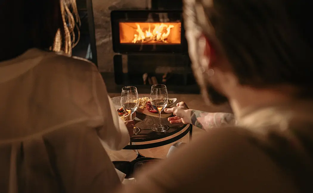 Un couple profite de la chaleur d'un poêle à bois bien allumé, parfait pour des soirées confortables après avoir utilisé la méthode du feu inversé.