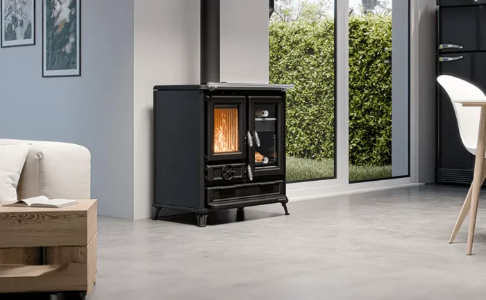 Cuisinière à bois Thermorossi Klarissa noire installée dans un salon moderne avec baie vitrée