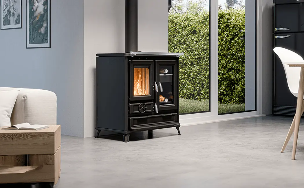 Cuisinière à bois Thermorossi Klarissa noire installée dans un salon moderne avec baie vitrée